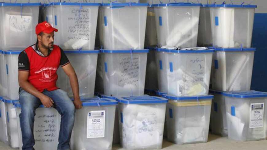 An employee of the Independent High Electoral Commission (IHEC) sits on ballot boxes at a tally center in Baghdad April 23, 2013.Voter participation in Iraq's provincial election on Saturday was 50 percent of eligible voters, the country's electoral authorities said after poll stations closed. Election officials said including results from a special vote a week earlier for members of the armed forces, total participation would be more than 51 percent. REUTERS/Mohammed Ameen (IRAQ - Tags: POLITICS ELECTIONS)