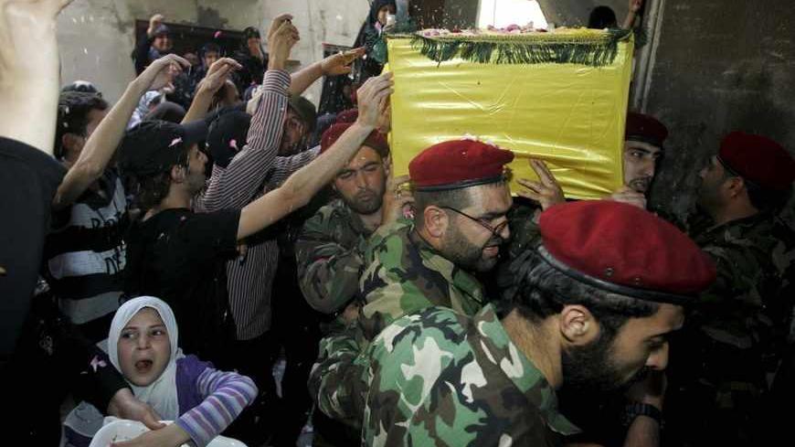 Supporters of Hezbollah and relatives of Hezbollah members throw rice on a coffin at the funeral of a Hezbollah fighter who died in the Syrian conflict in Ouzai in Beirut May 26, 2013. Hezbollah forces and Syrian President Bashar al-Assad's troops launched a fierce assault last week aimed at driving Syrian rebels out of Qusair, a strategic town close to the Lebanese border that rebels have used as a crucial supply corridor for weapons coming into Syria. REUTERS/Issam Kobeisy (LEBANON - Tags: POLITICS CONFLI