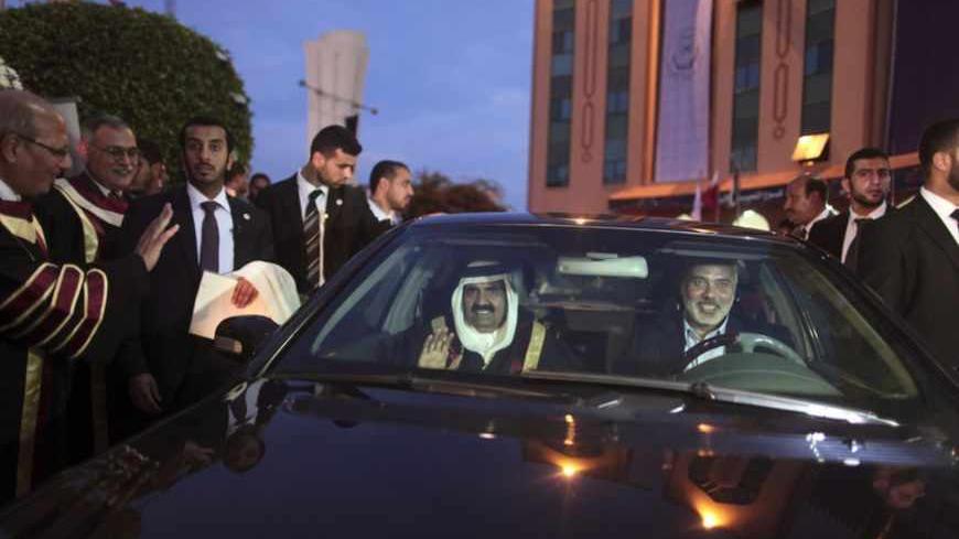 Hamas Prime Minister Ismail Haniyeh drives a car as the Emir of Qatar Sheikh Hamad bin Khalifa al-Thani sits next to him after a visit at the Islamic University in Gaza City October 23, 2012. The Emir of Qatar embraced the Hamas leadership of Gaza on Tuesday with an official visit that broke the isolation of the Palestinian Islamist movement, to the dismay of Israel and rival, Western-backed Palestinian leaders. REUTERS/Wissam Nassar/Pool (GAZA - Tags: POLITICS) - RTR39HDC