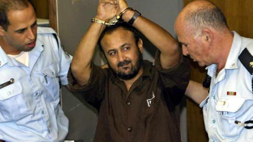 Marwan Barghouthi, head of the Palestinian Fatah Tanzim and al-Aksa Martyrs Brigades, gestures as Israeli police bring him into the District Court for his judgment hearing in Tel Aviv May 20, 2004. An Israeli court on Thursday convicted Barghouthi, a leader of the Palestinian uprising, on murder charges over the killing of five Israelis by militants.  REUTERS/Pool/David Silverman - RTRJYWL