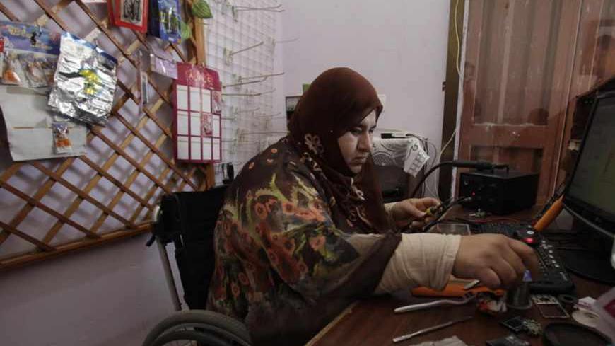 A wheelchair-bound Palestinian woman Manal al-Satari, 37, fixes cell phones at her shop in Rafah in the southern Gaza Strip April 7, 2013. 
REUTERS/Ibraheem Abu Mustafa (GAZA - Tags: SOCIETY) - RTXYBPS