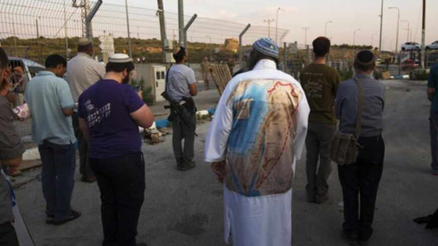 Jewish settlers, one of them wearing a garment printed with a map showing the borders of Biblical Israel, pray during a protest at the site of a stabbing attack by a Palestinian, at Tapuach junction, near the West Bank city of Nablus April 30, 2013. A Palestinian man stabbed and shot dead an Israeli settler in the occupied West Bank on Tuesday, the Israeli ambulance service and police said. REUTERS/Ronen Zvulun (WEST BANK - Tags: POLITICS CIVIL UNREST) - RTXZ5CZ