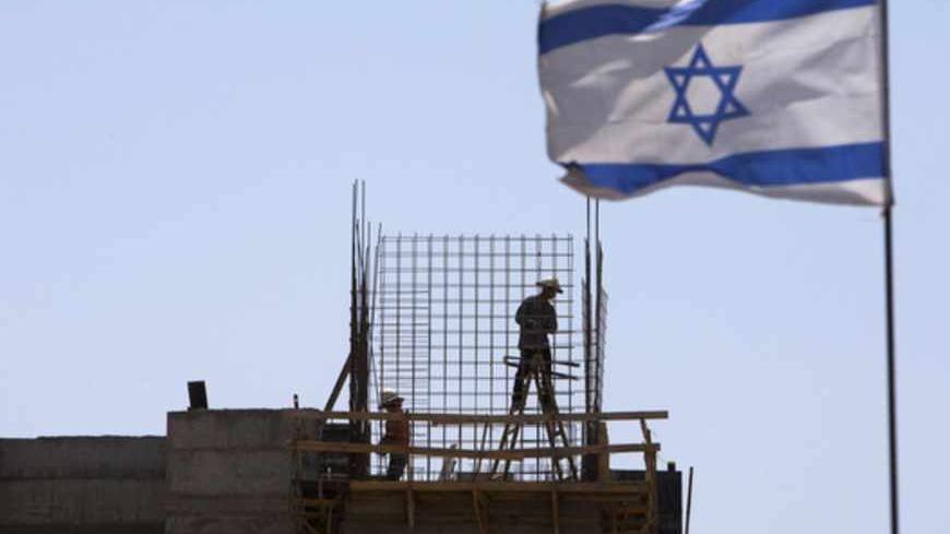 An Israeli flag is seen as labourers work on a construction site in a Jewish settlement near Jerusalem known to Israelis as Har Homa and to Palestinians as Jabal Abu Ghneim May 7, 2013. Prime Minister Benjamin Netanyahu has quietly curbed new building projects in Jewish settlements, an Israeli watchdog group and media reports said on Tuesday, in an apparent bid to help U.S. efforts to revive peace talks with the Palestinians. REUTERS/Ronen Zvulun (BUSINESS CONSTRUCTION POLITICS) - RTXZDIA