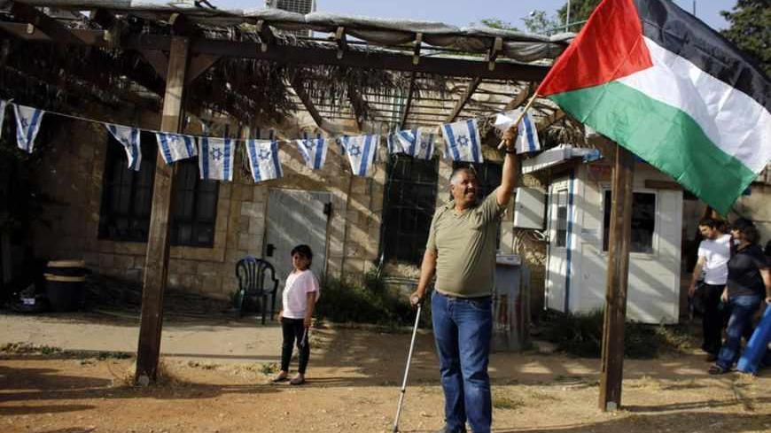 A Palestinian protester waves a Palestinian flag in the Sheikh Jarrah neighborhood of East Jerusalem May 17, 2013, during a weekly demonstration against Jewish settlements and the possible eviction of a Palestinian family from their home. REUTERS/Ammar Awad (JERUSALEM - Tags: POLITICS CIVIL UNREST) - RTXZQQH