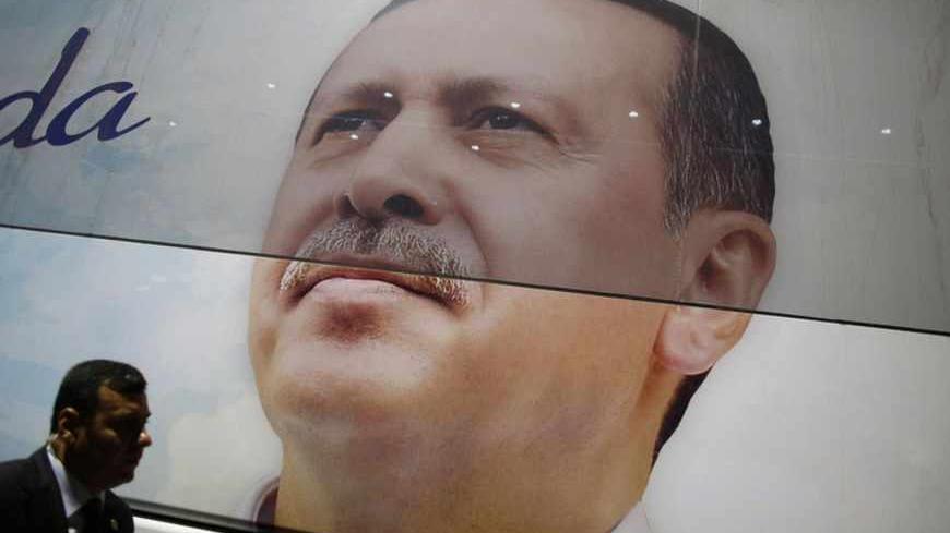 A Turkish secret service agent walks past an image of Turkish Prime Minister Tayyip Erdogan before his arrival at Istanbul's Ataturk airport June 6, 2013. Erdogan told thousands of cheering supporters on Friday his authority came from the ballot box and urged them not to be drawn into violence, in a show of ruling party strength after a week of fierce anti-government protests. Addressing crowds at Istanbul airport from an open-top bus after returning from a trip to North Africa, Erdogan called on his ruling