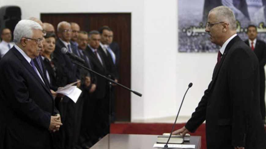 Palestinian Prime Minister Rami Hamdallah (R) stands in front of President Mahmoud Abbas during a swearing-in ceremony of the new government in the West Bank city of Ramallah June 6, 2013. Hamdallah and his West Bank-based government were sworn in on Thursday and one of their main challenges will be reaching a power-sharing deal with the Islamist Hamas movement ruling Gaza. REUTERS/Mohamad Torokman (WEST BANK - Tags: POLITICS) - RTX10E5M