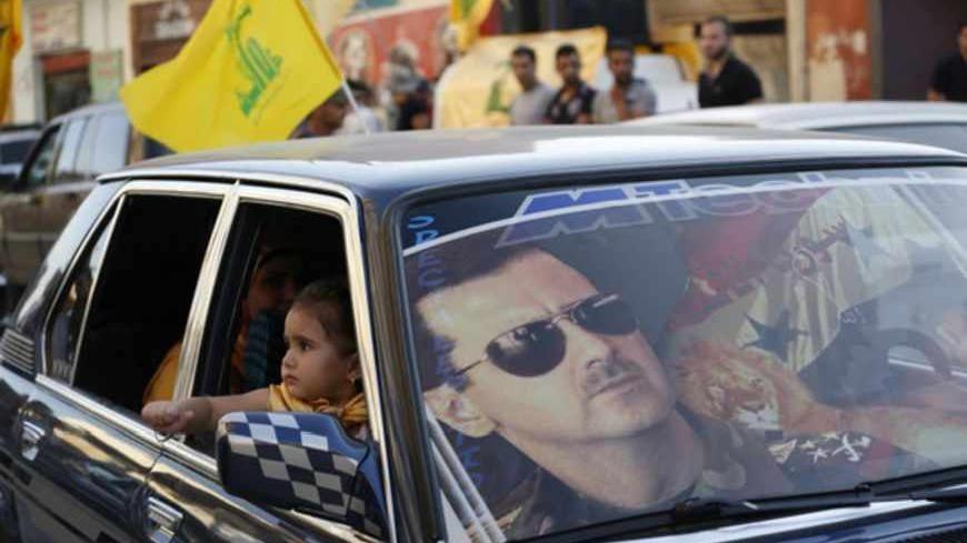 An image of Syria's President Bashar al-Assad is seen on a car's windscreen as Hezbollah supporters celebrate, after the Syrian army took control of Qusair from rebel fighters, in the Shi'ite town of Hermel June 5, 2013. Syrian government forces and their Lebanese Hezbollah allies seized control of the border town of Qusair on Wednesday, dealing a major defeat to rebel fighters battling to overthrow Assad. REUTERS/Jamal Saidi (LEBANON - Tags: POLITICS CIVIL UNREST MILITARY CONFLICT TPX IMAGES OF THE DAY) - 