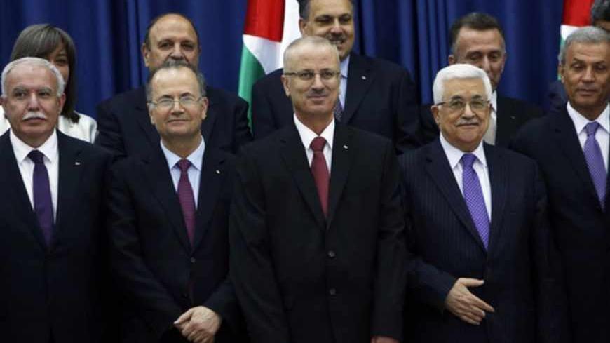 Palestinian President Mahmoud Abbas (front row R) stands next to Prime Minister Rami Hamdallah (C) and other ministers as they pose for a group photograph during a swearing-in ceremony of the new government in the West Bank city of Ramallah June 6, 2013. Hamdallah and his West Bank-based government were sworn in on Thursday and one of their main challenges will be reaching a power-sharing deal with the Islamist Hamas movement ruling Gaza. REUTERS/Mohamad Torokman (WEST BANK - Tags: POLITICS) - RTX10E4P