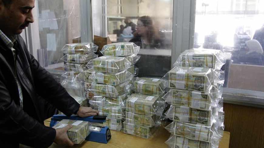 An employee seals bags of Syrian pound notes at the Syrian central bank in Damascus April 23, 2013. Picture taken April 23, 2013.        To match SYRIA-CURRENCY/        REUTERS/Khaled al-Hariri (SYRIA - Tags: POLITICS CONFLICT BUSINESS) - RTXYYBZ