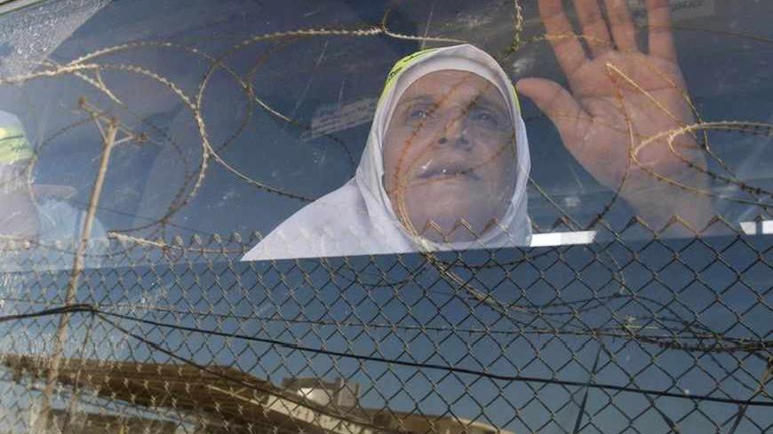 A Palestinian woman waves her hand as she sits in a bus before leaving Rafah border crossing for the annual haj pilgrimage in Mecca, in the southern Gaza Strip October 14, 2011.   REUTERS/Mohammed Salem (GAZA - Tags: POLITICS RELIGION TPX IMAGES OF THE DAY) - RTR2SO7F