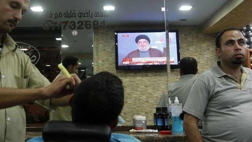 People in a barber shop watch Lebanon's Hezbollah leader Sayyed Hassan Nasrallah on a television as he addresses his supporters during iftar, the breaking of fast meal, during the Islamic month of Ramadan in Sidon, southern Lebanon July 24, 2013. Nasrallah said on Wednesday the European Union had given Israel justification to attack Lebanon by blacklisting the armed wing of his group, and would bear responsibility for any Israeli military action. REUTERS/Ali Hashisho (LEBANON - Tags: SOCIETY POLITICS RELIGI