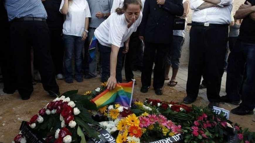 Chen Katz (C) places a rainbow flag on the grave of her brother Nir during his funeral in the Israeli city of Modiin near Tel Aviv August 2, 2009. Israel's gay community was rocked on Sunday by the killing of two people, one of them Katz, in a homosexual and lesbian youth centre and the possibility they fell victim to a hate crime in the Jewish state's most freewheeling city. REUTERS/Baz Ratner (ISRAEL POLITICS CONFLICT) - RTR26CSB