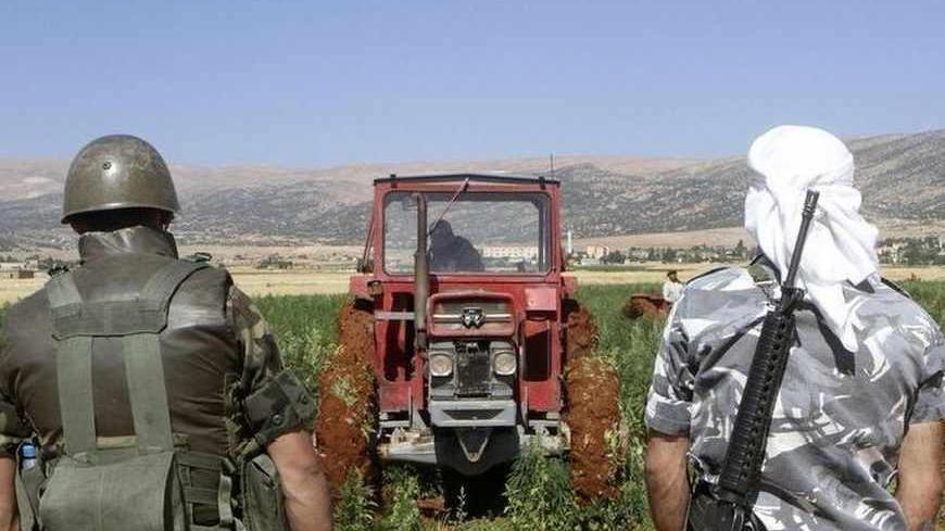 A soldier and a policeman secure a field as a man uses a tractor to uproot hashish plants in Boday village, near Baalbek city, July 23, 2012. Farmers armed with assault rifles, rocket-propelled grenades and mortars forced Lebanese government troops to abandon an operation to destroy their illegal cannabis crop in Lebanon's Bekaa Valley on Monday, a witness said. The farmers' attack halted a morning raid by security forces, who had been flattening the tall spiky marijuana plants with tractors, accompanied by