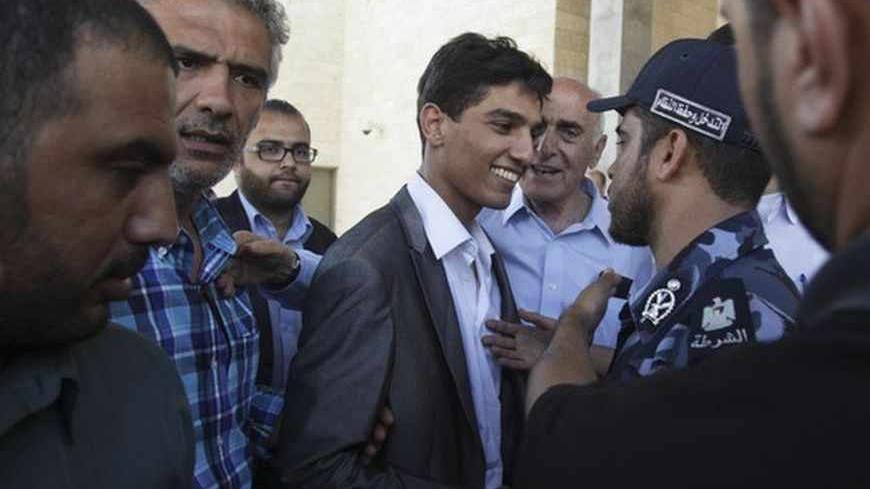 Palestinian "Arab Idol" Mohammed Assaf (C) is welcomed by a policeman loyal to Hamas upon his arrival in Gaza June 25, 2013. Tens of thousands of joyous fans turned out on Tuesday to welcome Assaf on his return to the Gaza Strip and the song contest winner appealed for harmony among divided Palestinians. REUTERS/Ibraheem Abu Mustafa (GAZA - Tags: ENTERTAINMENT POLITICS SOCIETY TPX IMAGES OF THE DAY) - RTX110G4