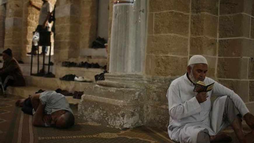 A Palestinian man recites the Koran as another man takes a nap at al-Omari mosque in Gaza City, during the first day of the holy fasting month of Ramadan July 10, 2013.  REUTERS/Mohammed Salem (GAZA - Tags: RELIGION) - RTX11ILF