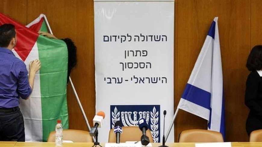 Israeli parliament employees set up a Palestinian flag (L) next to an Israeli one as they prepare ahead of a meeting between Israeli parliament members and a delegation of Palestinian politicians and businessmen, aimed at encouraging Israeli-Palestinian negotiations, at the Knesset, the Israeli parliament, in Jerusalem July 31, 2013. Israeli and Palestinian negotiators on Tuesday gave themselves about nine months to try reach an agreement on ending their conflict of more than six decades in U.S.-brokered pe