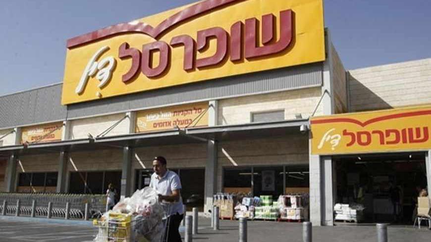A man pushes a shopping cart outside a Super-Sol supermarket in the West Bank Jewish settlement of Mishor Adumim near Jerusalem May 5, 2013. Ten large business groups, including Israeli tycoon Nochi Dankner's IDB conglomerate, control about 30 percent of the market value of public companies in Israel. Super-Sol, Israel's largest supermarket chain, is part of Dankner's conglomerates'  pyramid. Picture taken May 5, 2013. To match ISRAEL-ECONOMY/TYCOONS   REUTERS/Ammar Awad (WEST BANK - Tags: BUSINESS POLITICS