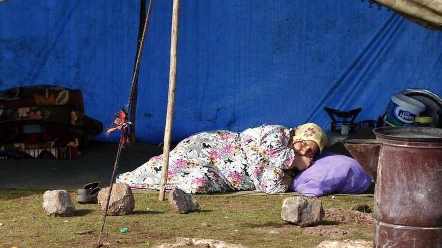 A Syrian refugee woman lies down as she rests in front of her makeshift tent in the town of Viransehir in Sanliurfa province, southeast Turkey, February 10, 2013. Some 50 families, mostly from villages near Syria's Aleppo, prefer to settle in the outskirts of Viransehir instead of refugee camps run by the Turkish government. According to the families, this allows them to work as seasonal agricultural workers.  REUTERS/Umit Bektas (TURKEY - Tags: POLITICS SOCIETY CIVIL UNREST BUSINESS EMPLOYMENT) - RTR3DL0G