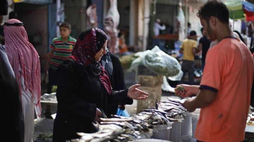 A Palestinian woman buys traditional fish eaten during Eid, ahead of the Muslim Eid al-Fitr holiday, at a market in Khan Younis in the southern Gaza Strip August 7, 2013. REUTERS/Ibraheem Abu Mustafa (GAZA - Tags: RELIGION ANNIVERSARY) - RTX12COG