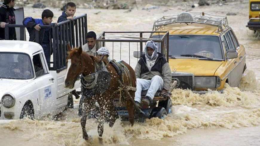Palestinians ride on a horse cart in the Gaza valley area, flooded after heavy rain overnight, in central Gaza Strip December 29, 2006.  REUTERS/Ibraheem Abu Mustafa (GAZA) - RTR1KQKE