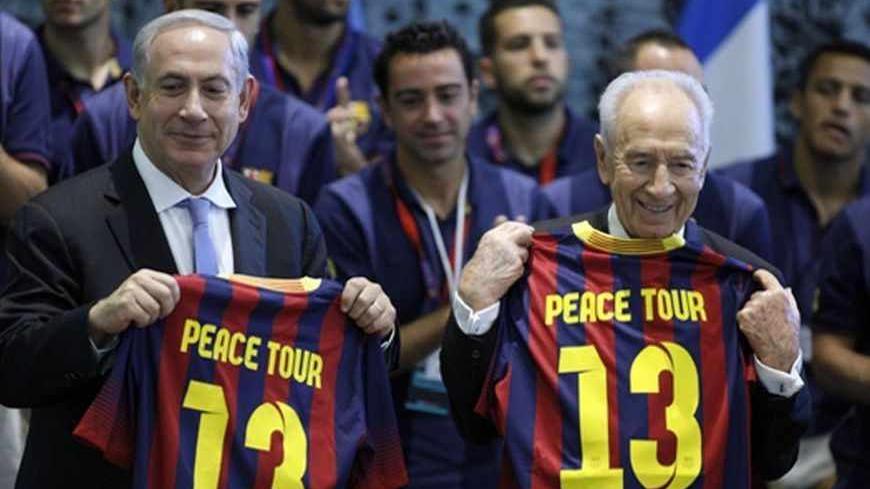 Israel's President Shimon Peres (R) and Prime Minister Benjamin Netanyahu hold Barcelona soccer jerseys as they stand in front of the players during a reception at Peres' residence in Jerusalem August 4, 2013. The Spanish league champions are making a brief stopover in Israel and the Palestinian territories en-route to a pre-season tour of Asia. REUTERS/Lior Mizrahi/Pool (JERUSALEM - Tags: POLITICS SPORT SOCCER TPX IMAGES OF THE DAY) - RTX12A43