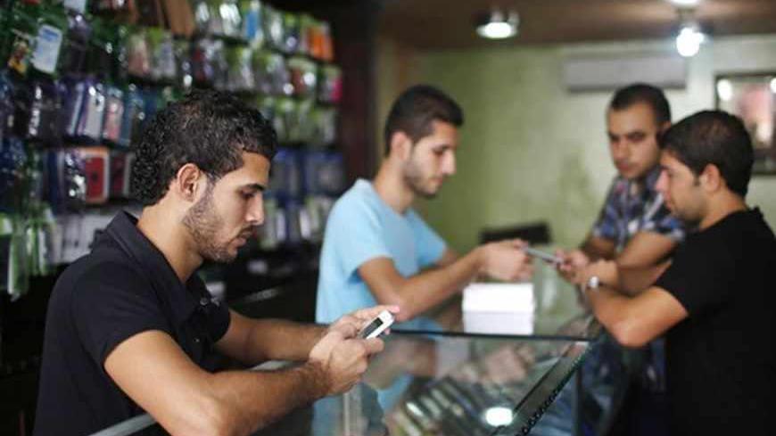 A Palestinian salesperson holds Apple's new iPhone 5 at a mobile phone store in Gaza City October 16, 2012. Apple's new iPhone 5 is selling well in the Gaza Strip despite inflated prices, reaching the Palestinian enclave via smuggling tunnels even before high-tech hub Israel next door.   REUTERS/Mohammed Salem (GAZA - Tags: POLITICS SCIENCE TECHNOLOGY BUSINESS SOCIETY TELECOMS) - RTR3970R