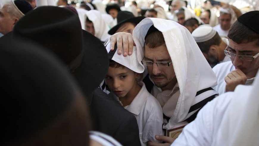 A Jewish worshipper covers himself and a young boy with a prayer shawl as they recite the priestly blessing at the Western Wall, Judaism's holiest prayer site, during the holiday of Sukkot in Jerusalem's Old City October 3, 2012.    
REUTERS/Darren Whiteside  (JERUSALEM - Tags: RELIGION) - RTR38QJY