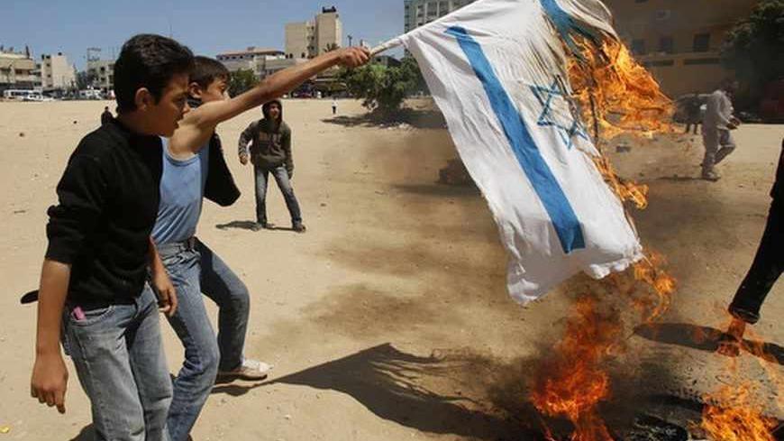 A Palestinian boy burns an Israeli flag as he performs a scene simulating clashes with Israeli soldiers, in solidarity with Palestinian prisoners held in Israeli jails, in Gaza City April 14, 2013.  REUTERS/Suhaib Salem (GAZA - Tags: POLITICS CIVIL UNREST) - RTXYL66