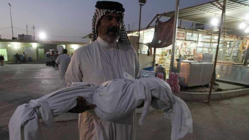 An Iraqi man carries the body of his son, who was killed by a car bomb attack, during a funeral in Najaf, 160 km (100 miles) south of Baghdad, August 15, 2013. A series of car bombs in Baghdad killed at least 33 people and wounded more than 100 on Thursday, police sources said. The Interior Ministry put the death toll far lower, saying only three people were killed and 44 wounded in the violence.   REUTERS/Haider Ala (IRAQ - Tags: CIVIL UNREST POLITICS) - RTX12MX2