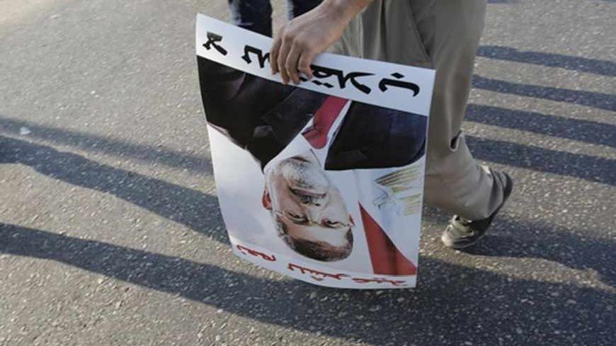 A supporter of deposed Egyptian President Mohamed Mursi holds a poster of him during a protest along Zahara street in Cairo August 18, 2013. Egypt's army-backed rulers met on Sunday to discuss their bloody confrontation with deposed President Mohamed Mursi's Muslim Brotherhood amid contrasting proposals for compromise and a fight to the death. REUTERS/Youssef Boudlal (EGYPT - Tags: POLITICS CIVIL UNREST) - RTX12Q2U