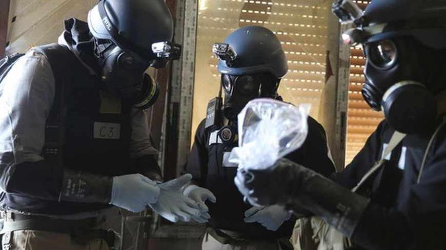 A U.N. chemical weapons expert, wearing a gas mask, holds a plastic bag containing samples from one of the sites of an alleged chemical weapons attack in the Ain Tarma neighbourhood of Damascus August 29, 2013. A team of U.N. experts left their Damascus hotel for a third day of on-site investigations into apparent chemical weapons attacks on the outskirts of the capital. Activists and doctors in rebel-held areas said the six-car U.N. convoy was scheduled to visit the scene of strikes in the eastern Ghouta s
