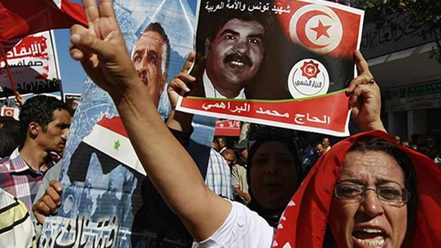 Protesters hold up and a picture of slain opposition leader Mohamed Brahmi during an anti-government demonstration rallying for the dissolution of the Islamist-led government in Sfax, 170 miles (270 km) southeast of Tunis September 26, 2013. Thousands protested in cities across Tunisia on Thursday to call on the ruling Islamist Ennahda party to step down immediately to make way for new elections to end a stalemate with its secular opponents. Poster reads, "Mohamed Brahmi: The martyr of Tunis and the Arab st