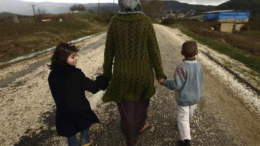 Sawssan  Abdelwahab, who fled Idlib in Syria, walks with her children outside the refugees camp near the Turkish-Syrian border in the southeastern city of Yayladagi February 16, 2012. REUTERS/Zohra Bensemra (TURKEY - Tags: CIVIL UNREST POLITICS) - RTR2XYH9