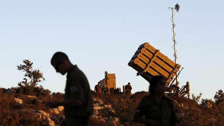 Israeli soldiers walk next to an Iron Dome missile interceptor battery as it is being positioned on the outskirts of Jerusalem, September 8, 2013 REUTERS/ Ammar Awad (JERUSALEM - Tags: CONFLICT POLITICS CIVIL UNREST MILITARY) - RTX13D0G