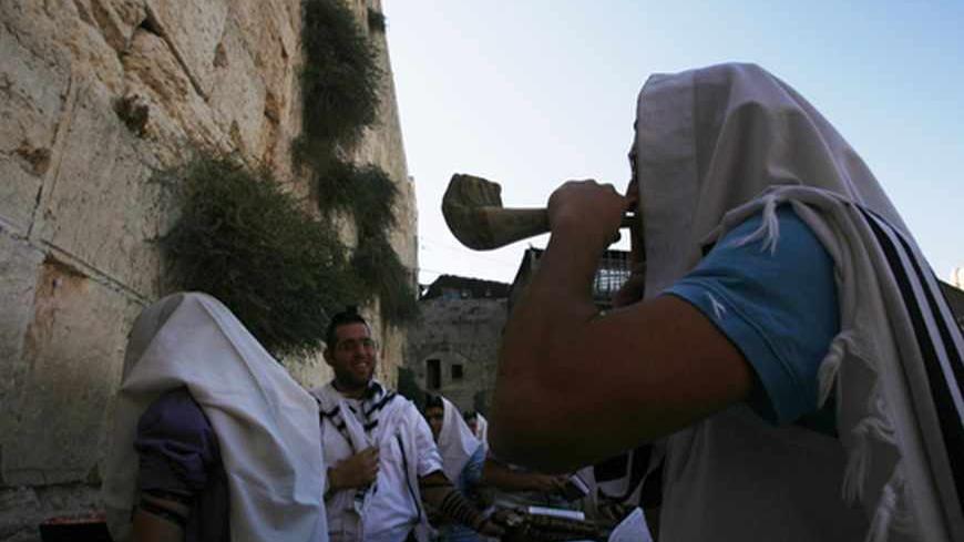 A Jewish worshipper covered in a prayer shawl blows a shofar, or a ram's horn, during prayers at the Western Wall, Judaism's holiest prayer site, in the Old City of Jerusalem September 27, 2011, ahead of Rosh Hashanah, the Jewish New Year, which starts at sundown on Wednesday. REUTERS/Baz Ratner (JERUSALEM - Tags: SOCIETY RELIGION) - RTR2RW7H