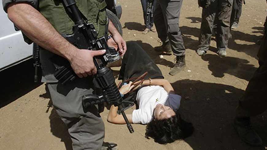 French diplomat Marion Castaing lays on the ground after Israeli soldiers carried her out of her truck, in the West Bank herding community of Khirbet al-Makhul, in the Jordan Valley September 20, 2013. Israeli soldiers manhandled European diplomats, including Castaing, on Friday and seized the truck full of tents and emergency aid they had been trying to deliver to Palestinians whose homes were demolished earlier this week. REUTERS/Abed Omar Qusini (WEST BANK - Tags: POLITICS CIVIL UNREST MILITARY) - RTX13S