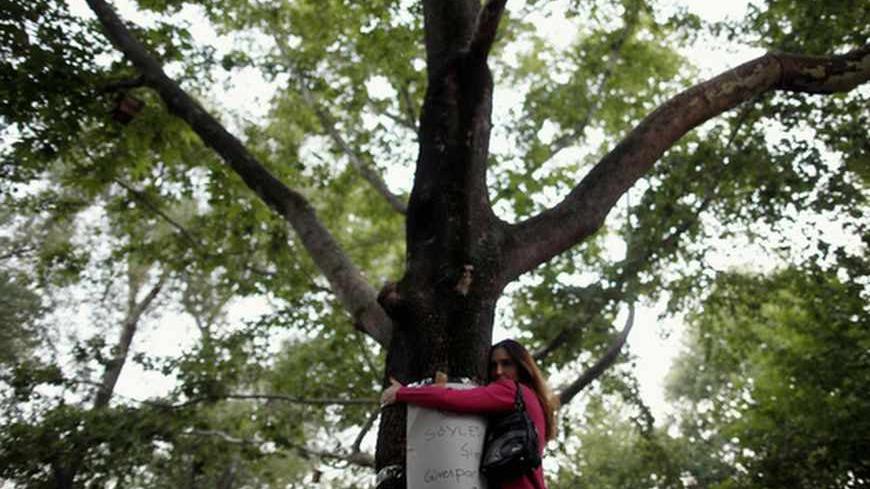 A woman hugs a tree in silence during a protest at Kugulu park in central Ankara June 18, 2013. Overnight in Ankara, riot police used tear gas and water cannon to disperse hundreds of protesters who had gathered in and around the government quarter of Kizilay. But in stark contrast to the recent fierce clashes in several cities, dozens of protesters merely stood in silence in Istanbul, Ankara and Izmir, inspired by a man who lit up social media by doing just that for eight hours in Istanbul's Taksim Square 