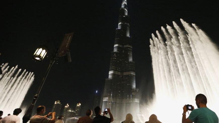 People watch a fountain in front of Burj Khalifa, currently the tallest building in the world, in Dubai October 9, 2013. A stampede by competing apartment buyers in Dubai this week may have obscured signs that Dubai's latest real estate boom is more restrained than the last one, which pushed the government close to default.    REUTERS/Ahmed Jadallah (UNITED ARAB EMIRATES - Tags: REAL ESTATE BUSINESS CITYSCAPE) - RTX1459Q