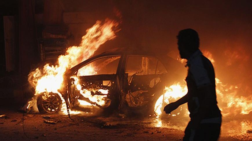 A man looks at a car on fire at the site of a bomb attack in Baghdad October 7, 2013. Bombs exploded across the Iraqi capital Baghdad on Monday, killing at least 22 people, police said. Five of the six blasts were in mainly Shi'ite Muslim districts, but there was also an explosion in the predominantly Sunni Muslim neighborhood of Doura.  REUTERS/Ahmed Saad (IRAQ - Tags: POLITICS CIVIL UNREST TPX IMAGES OF THE DAY) - RTX142ZK