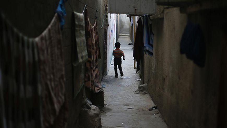 A Palestinian refugee boy walks between the narrow alleys of Jabalya refugee camp in the northern Gaza Strip May 14, 2013. Palestinians will mark "Nakba" (Catastrophe) on May 15 to commemorate the expulsion or fleeing of some 700,000 Palestinians from their homes in the war that led to the founding of Israel in 1948. REUTERS/Suhaib Salem (GAZA - Tags: CIVIL UNREST POLITICS) - RTXZM8H