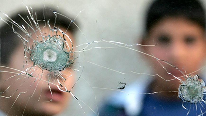 Iraqi boys are seen through the broken window of a car which was damaged in mortar attack in southwest Baghdad, December 11, 2006. REUTERS/Namir Noor-Eldeen (IRAQ) - RTR1KAON