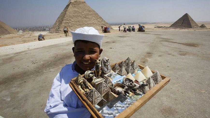 A child vendor waits for tourists to sell them souvenirs at the Giza Pyramids, on the outskirts of Cairo August 26, 2013. REUTERS/Youssef Boudlal (EGYPT - Tags: SOCIETY TRAVEL) - RTX12XFC