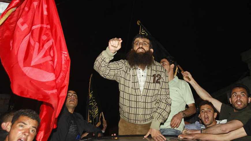 Khader Adnan (C), a member of Islamic Jihad, stands in a vehicle upon his arrival in the West Bank village of Arabe near Jenin after his release from an Israeli prison April 17, 2012. Adnan, a prisoner who refused food for 66 days before agreeing to a deal under which he was released late on Tuesday, was greeted by hundreds of supporters when he reached his hometown in the West Bank. Picture taken April 17, 2012. REUTERS/Abed Omar Qusini (WEST BANK - Tags: POLITICS) - RTR30VOO