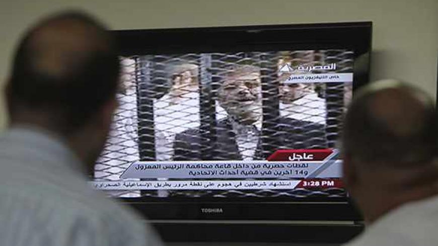 Egyptians watch TV showing the trial of ousted Egyptian president Mohamed Mursi, in Cairo November 4, 2013. Mursi struck a defiant tone on the first day of his trial on Monday, chanting 'Down with military rule', and calling himself the country's only 'legitimate' president. Mursi, an Islamist who was toppled by the army in July after mass protests against him, appeared angry and interrupted the session repeatedly, prompting a judge to adjourn the case. REUTERS/Mohamed Abd El Ghany (EGYPT - Tags: POLITICS C