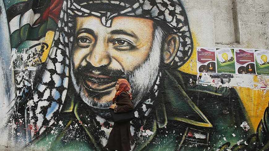 A Palestinian student walks past a mural depicting late Palestinian leader Yasser Arafat in Gaza City November 7, 2013. Swiss scientists who conducted tests on the remains of Palestinian leader Yasser Arafat, whose widow Suha says he was poisoned by radioactive polonium, will give a news conference on Thursday on their findings. REUTERS/Suhaib Salem (GAZA - Tags: POLITICS CRIME LAW SOCIETY) - RTX153OJ
