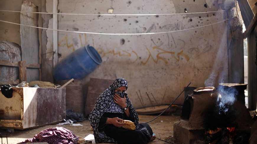 A Palestinian woman bakes bread inside her house, which she said was damaged during an Israeli air strike on a nearby smuggling tunnel during an eight-day conflict with Israel last year, in Rafah in the southern Gaza Strip November 13, 2013, ahead of the first anniversary of the conflict. Eight days of Israeli air strikes on Gaza and cross-border Palestinian rocket attacks in November last year ended in an Egyptian-brokered truce agreement calling on Israel to ease restrictions on the territory. REUTERS/Ibr
