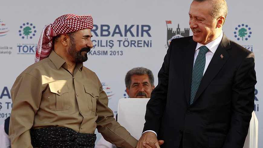Turkey's Prime Minister Tayyip Erdogan (R) chats with Kurdish poet and singer Sivan Perwer (L), who had fled Turkey in the 1970s,  during a ceremony in Diyarbakir November 16, 2013.  The president of Iraqi Kurdistan called on Turkey's Kurds to back a flagging peace process with Ankara on Saturday, making his first visit to southeastern Turkey in two decades in a show of support for Prime Minister Erdogan. Masoud Barzani's trip to Diyarbakir, the main city in Turkey's Kurdish-dominated southeast, comes as An