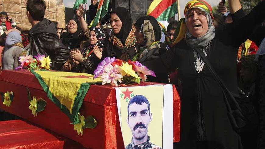 A woman stands beside the coffin of a Kurdish People's Protection Units (YPG) soldier who died fighting the al-Qaeda linked Islamic State of Iraq and the Levant, and Islamist Syrian rebel group Jabhat al-Nusra in Qamishli November 14, 2013. Picture taken November 14, 2013. REUTERS/Massoud Mohammed (SYRIA - Tags: POLITICS CIVIL UNREST CONFLICT) - RTX15H58