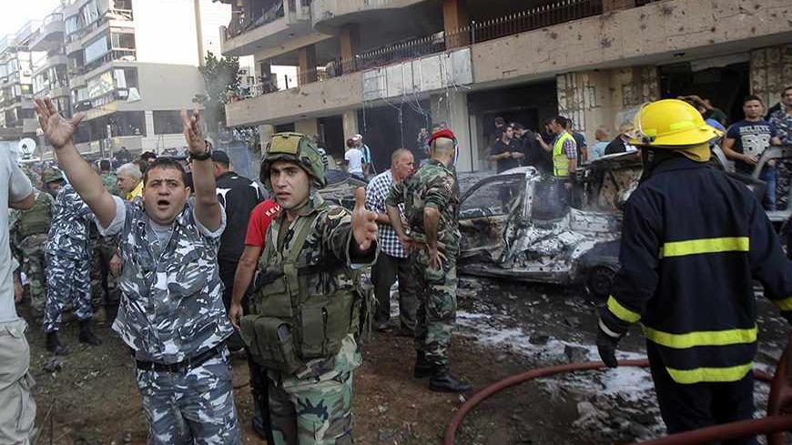 A soldier (in green, 2nd L) and policeman gesture at the site of the explosions near the Iranian embassy in Beirut November 19, 2013. Two explosions apparently targeting the Iranian embassy hit the capital Beirut on Tuesday, security sources said, damaging at least six buildings in the embassy compound. REUTERS/Mahmoud Kheir    (LEBANON - Tags: POLITICS CIVIL UNREST) - RTX15JOA