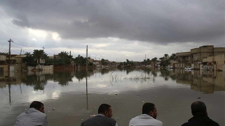 People sit on high ground watching their submerged houses after heavy rain fell in Najaf, 160 km (100 miles) south of Baghdad, November 20, 2013. REUTERS/ Ahmad Mousa   (IRAQ - Tags: ENVIRONMENT DISASTER) - RTX15LZF